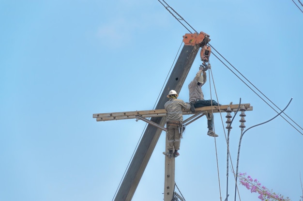 Homens técnicos consertando ou reparando linhas elétricas quebradas em postes elétricos trabalho altamente perigoso