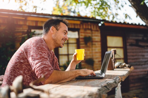 Foto homens tomando café e usando o laptop no pátio do quintal