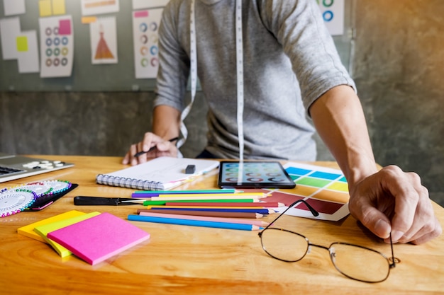 Homens trabalhando como designer de moda escolhendo no gráfico de cores para roupas em tablet digital no estúdio do local de trabalho.