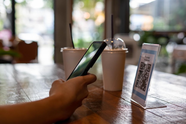 Homens usam telefones para digitalizar um código qr para selecionar um menu ou digitalizar para receber um desconto ou pagar por comida e bebida dentro de um café usando o telefone para transferir dinheiro ou pagar on-line sem conceito de dinheiro