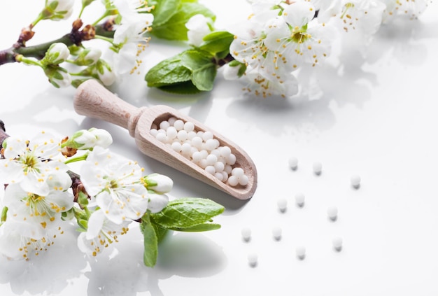 Homöopathische Pillen mit Frühlingsblumen auf weißem Holzhintergrund