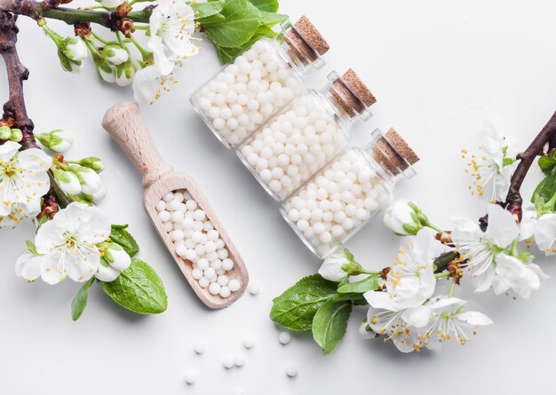 Homöopathische Pillen mit Frühlingsblumen auf weißem Holzhintergrund