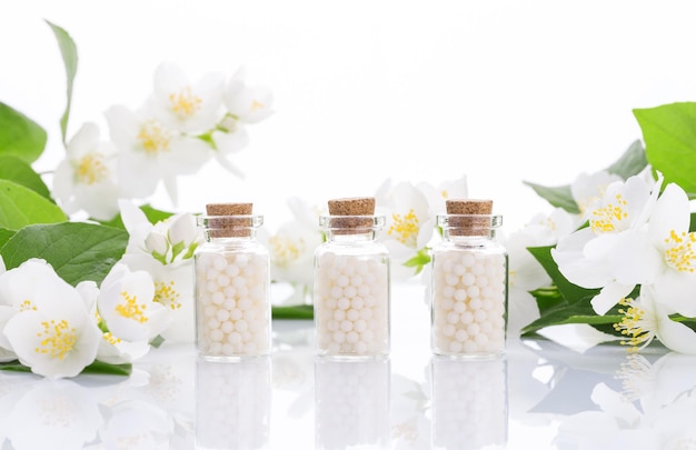 Homöopathische Pillen mit Frühlingsblumen auf weißem Holzhintergrund