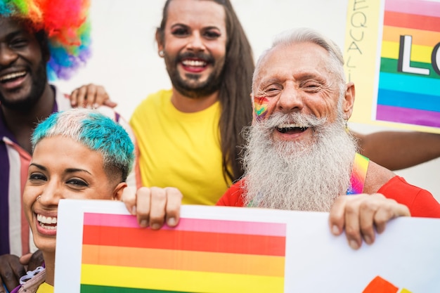 Homosexuelle Menschen, die Spaß an der Stolzparade mit LGBT-Banner im Freien haben - Hauptfokus auf Gesicht des älteren Mannes