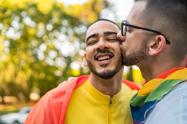 Homosexuelles Paar, das ihre Liebe mit Regenbogenfahne umarmt und zeigt