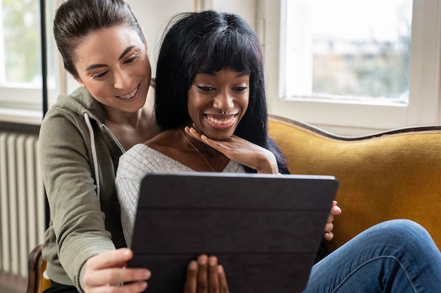 Homosexuelles Paar junger Frauen, die sich zu Hause umarmen, während sie Videos oder Fernsehserien auf dem Tablet ansehen Intimer Moment zwischen zwei lesbischen Mädchen beim Online-Shopping Lgbtq-Beziehungskonzept