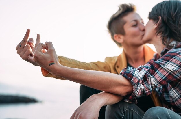 Foto homosexuelles paar küsst sich, während es die mittelfinger im freien zeigt