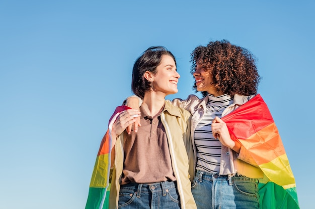 Homosexuelles Paar reizender Frauen mit einer Regenbogenfahne