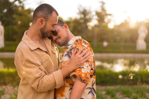 Homosexuelles Paar umarmt sich lächelnd bei Sonnenuntergang in einem Park in der Stadt Vielfalt und LGBT-Konzept