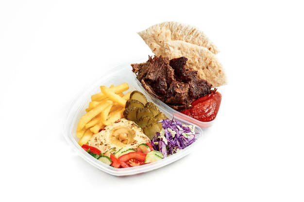Homus combinado de menu com salada de legumes batatas fritas pita e shawarma de carne em uma tigela de plástico sobre fundo branco