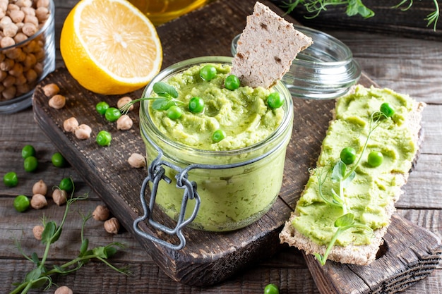 Homus de salsa verde com grão de bico, ervilha verde e grão de bico caseiro em uma mesa de madeira. Deliciosa comida saudável