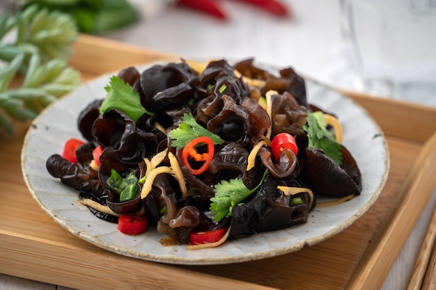 Hongo negro de árbol comestible hervido, oreja de madera en un plato sobre la mesa blanca