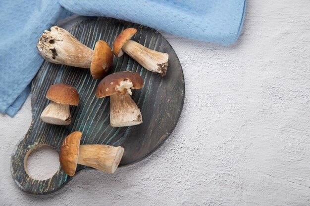 Los hongos porcini del bosque yacen sobre una tabla redonda de madera sobre un fondo claro