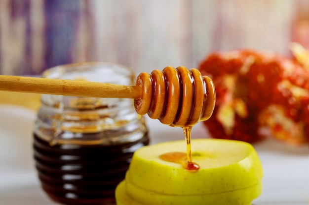 Honig, Apfel und Granatapfel auf Holztisch über Bokeh-Hintergrund