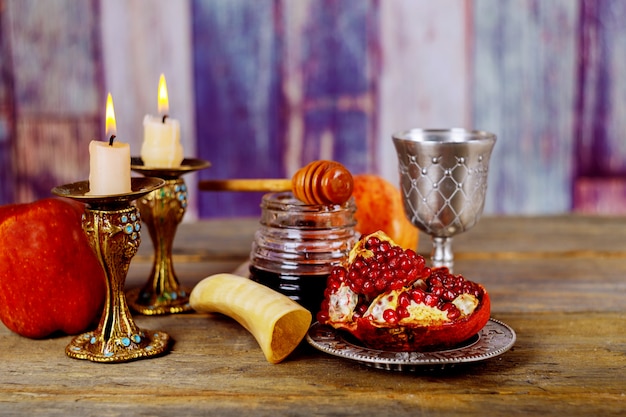 Honig, Apfel und Granatapfel auf Holztisch über Bokeh-Hintergrund