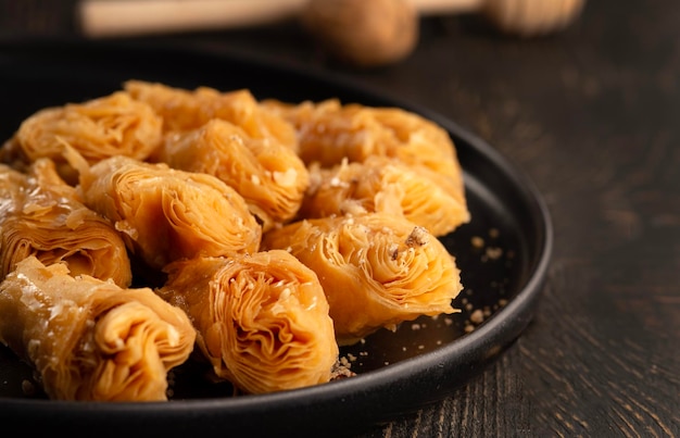 Honig-Baklava mit Walnüssen in einer schwarzen Platte, Nahaufnahme auf dunklem Holzhintergrund