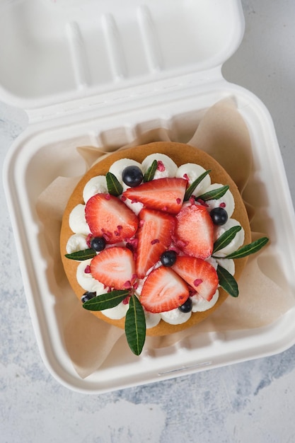 Foto honig-bento-kuchen, dekoriert mit sahne und frischen erdbeeren und heidelbeeren