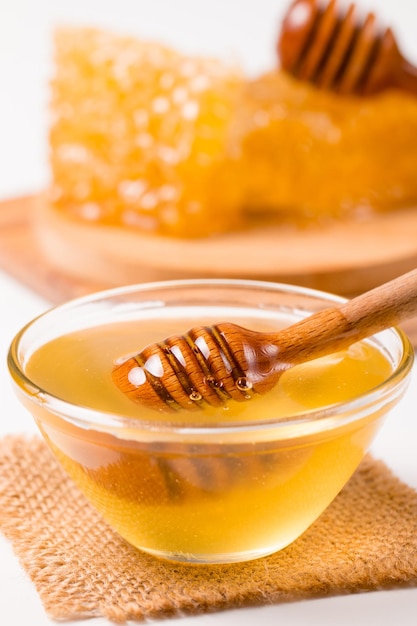 Honig, der von einem hölzernen Honigschöpflöffel auf weißem Hintergrund tropft. Gesundes Bio-Lebensmittelkonzept.