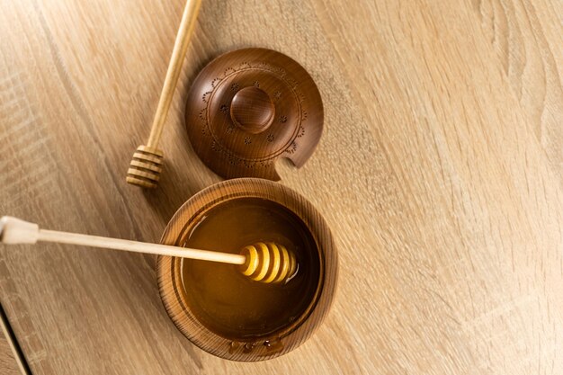 Honig mit Holzhonigschöpflöffel in Holzschale auf Holztisch.