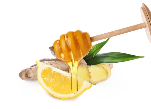 Honig tropft vom Schöpflöffel geschnittene Zitrone und Ingwerwurzel auf weißem Hintergrund