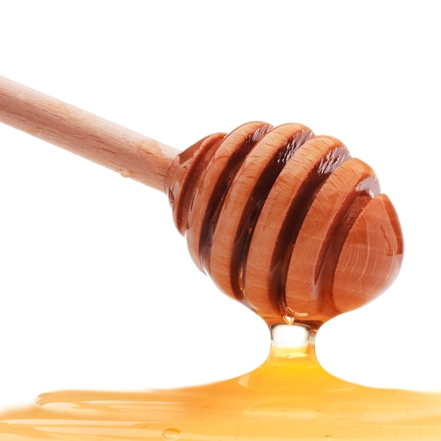 Honig tropft von einem hölzernen Honigschöpflöffel lokalisiert auf weißem Hintergrundausschnitt