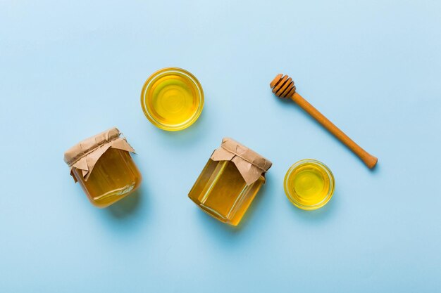Honigglas mit Holzdrizzler auf farbigem Hintergrund Honigtopf und Schöpflöffel hoch über dem Kopierbereich von oben