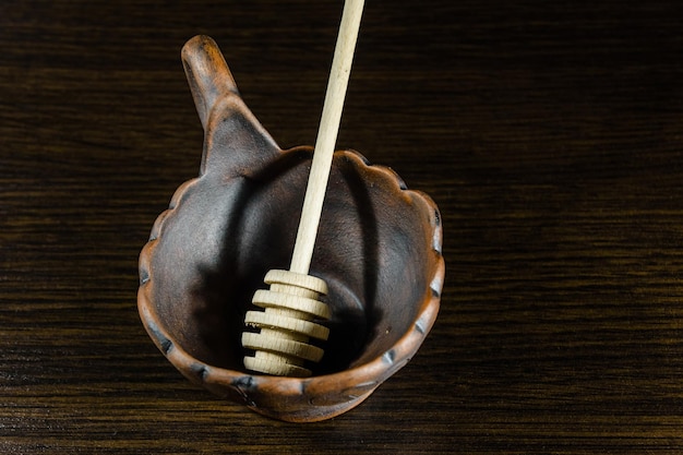 Honiglöffel in der Keramikschale auf dunklem Holztisch