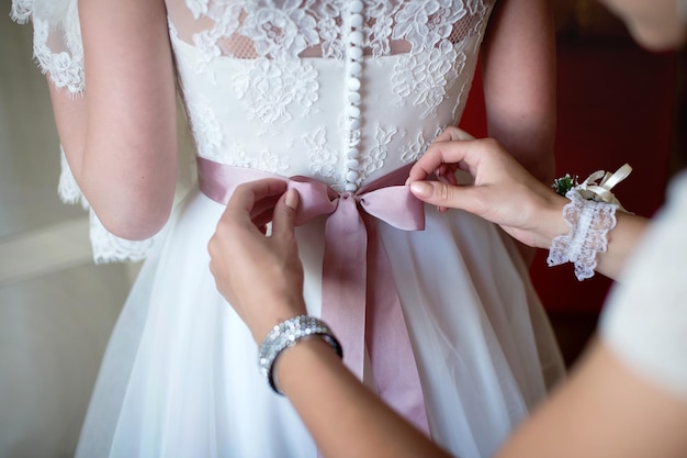 Los honorarios de la boda de la novia las damas de honor ayudan a ponerse un vestido.