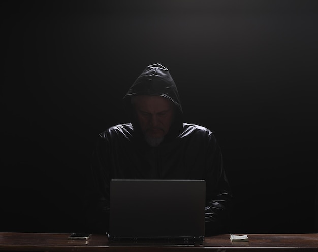 Hooded Hacker mit Laptop in der Nacht