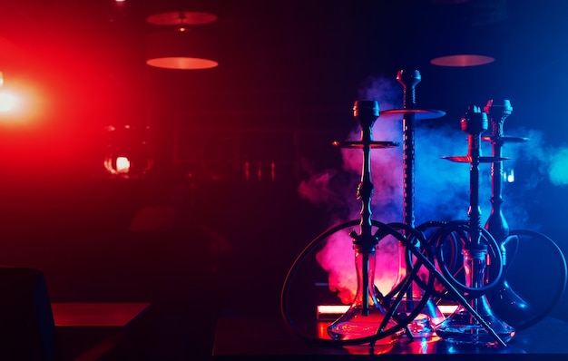 Hookahs en la mesa con humo en el salón de la cafetería