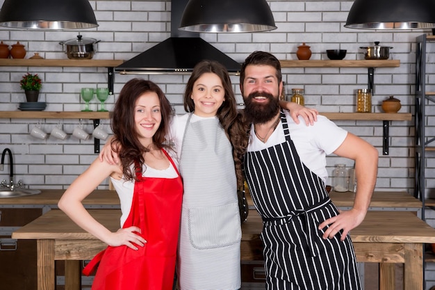 Hora del almuerzo feliz día de la familia asistencia mutua y apoyo familia amistosa en la cocina cocinando comida saludable en casa niño chef con sus padres Madre y padre enseñando a su hija a cocinar