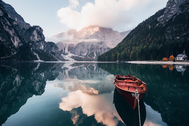 Hora del atardecer Barco de madera en el lago de cristal con majestuosa montaña detrás. Reflejo en el agua. Capilla está en la costa derecha