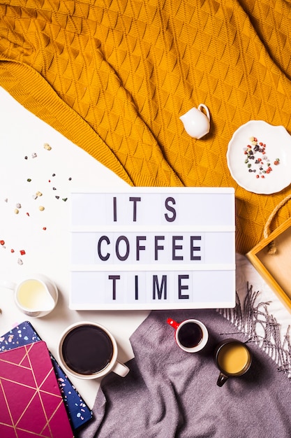 Foto la hora del café está escrita en una lámpara decorativa entre las muchas tazas de café.