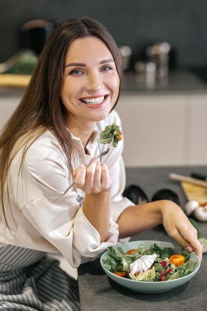 Foto hora de comer. sonriente mujer feliz comiendo con apetito