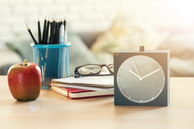 É hora da escola, despertador Vintage e maçã na mesa de madeira