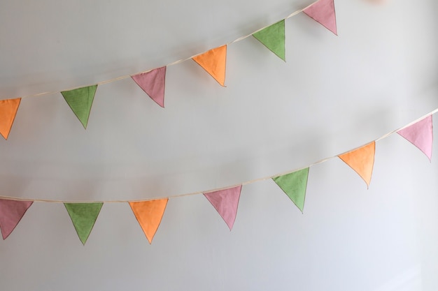 Foto hora da festa - guirlanda colorida feita de bandeiras triangulares de têxteis penduradas no fundo branco da parede