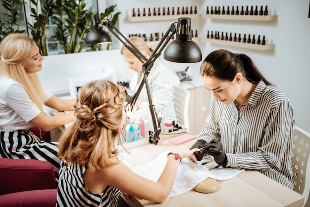 Hora da manicure. Mãe e filha loira estilosa indo ao salão de beleza para fazer as unhas