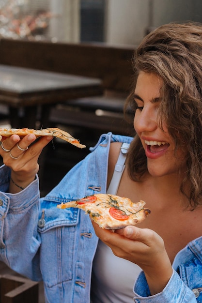 Foto hora da pizza mulher muito sorridente comendo pizza no restaurante