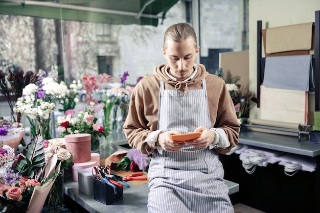 Hora de descansar. Florista gentil em seu local de trabalho e esperando por seu cliente