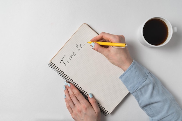Hora de escrever no caderno sobre fundo branco A fêmea entrega o bloco de notas e a xícara de café