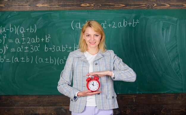 Hora de estudar Professor de boas-vindas ano letivo Educador experiente começa a aula Que horas são Ela se preocupa com a disciplina Professora segura despertador Garota professora de escola de roupa formal