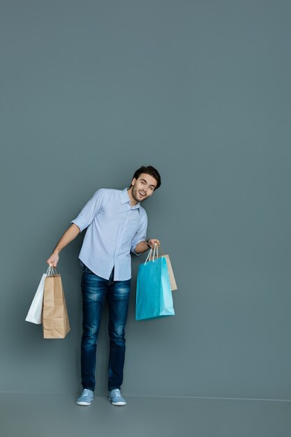 Hora de fazer compras. Homem simpático e alegre sorrindo e segurando sacolas enquanto visita lojas