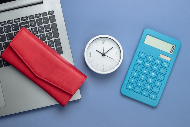 É hora de ganhar dinheiro. Negócio online. Relógio branco, laptop, calculadora e carteira vermelha sobre fundo roxo. Vista do topo. Postura plana