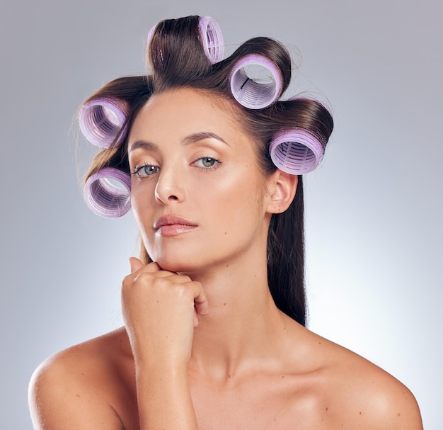 Hora de obter algum volume na foto de uma jovem atraente sozinha no estúdio e posando com rolos no cabelo