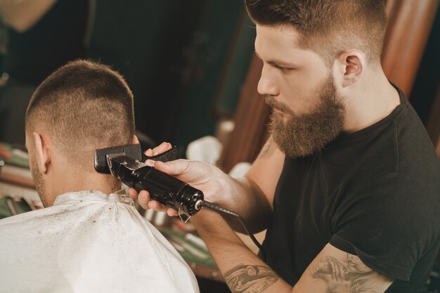 Hora de se arrumar. Tiro horizontal de um barbeiro profissional, dando um corte de cabelo para seu cliente