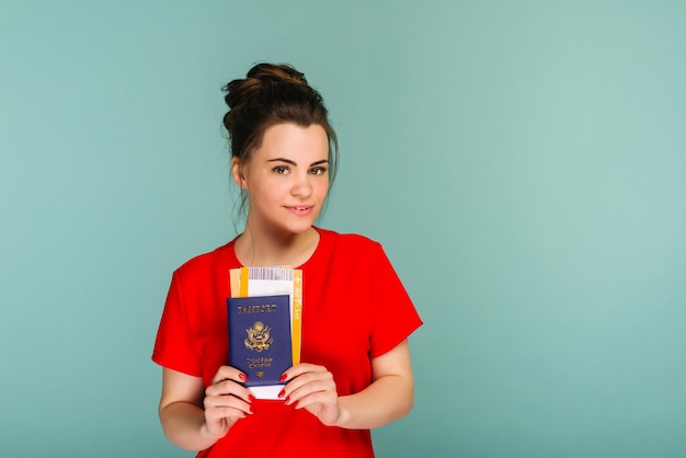 É hora de viajar Uma mulher moderna e sorridente de vestido vermelho com passagens aéreas e um passaporte na mão