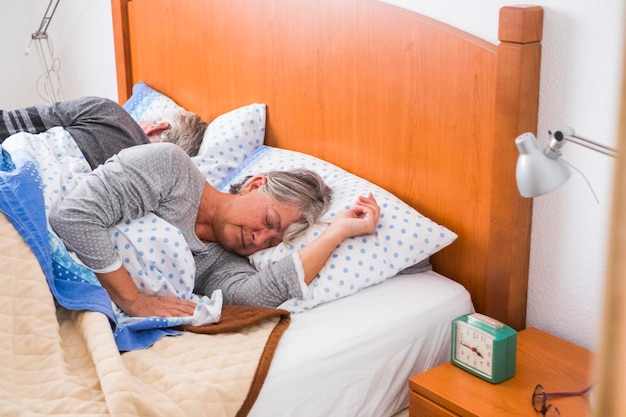 Hora de despertarse por la mañana para una pareja adulta mayor en casa en la cama dormir juntos a la luz de la ventana concepto de vida diurna personas caucásicas jubiladas