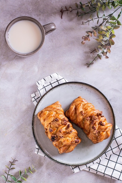 Hora do fika sueco com pãezinhos de canela frescos e uma xícara de café com leite no tampo da mesa e vista vertical