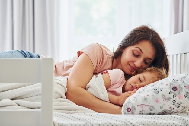 Hora de dormir Joven madre con su pequeña hija en ropa informal juntos en casa