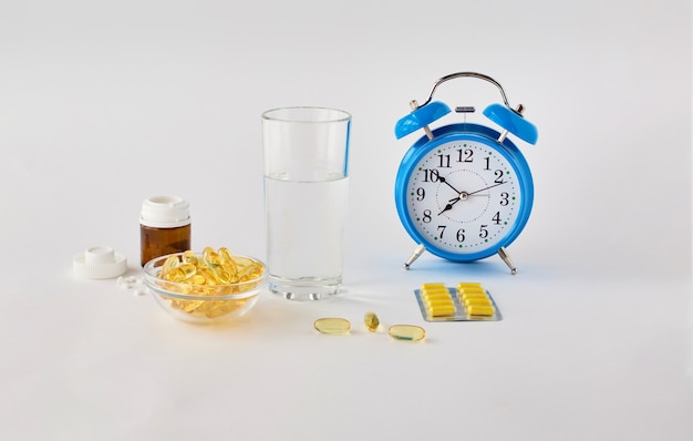 Hora de tomar las pastillas Un reloj despertador sobre un fondo blanco muestra la hora de tomar la medicación